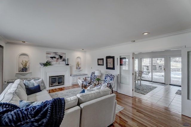 living area featuring a fireplace with flush hearth, recessed lighting, light wood finished floors, and ornamental molding