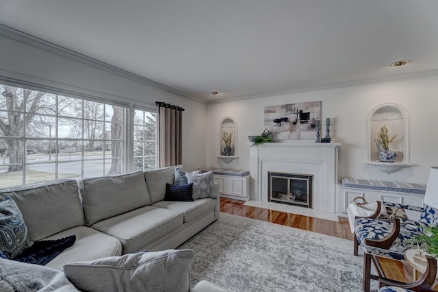 living area with a fireplace with flush hearth, crown molding, and wood finished floors