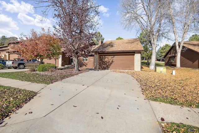 view of front facade featuring brick siding, a chimney, concrete driveway, and an attached garage