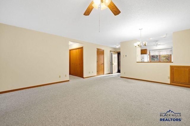 unfurnished room featuring a textured ceiling, ceiling fan with notable chandelier, baseboards, and light carpet