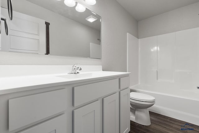 bathroom with vanity, toilet, wood finished floors, and shower / washtub combination