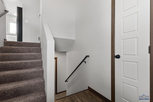 staircase with visible vents, baseboards, and wood finished floors