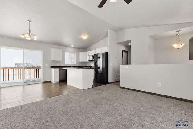 kitchen with open floor plan, dark carpet, lofted ceiling, stainless steel appliances, and white cabinetry