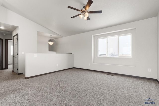 carpeted spare room featuring visible vents, baseboards, lofted ceiling, and a ceiling fan