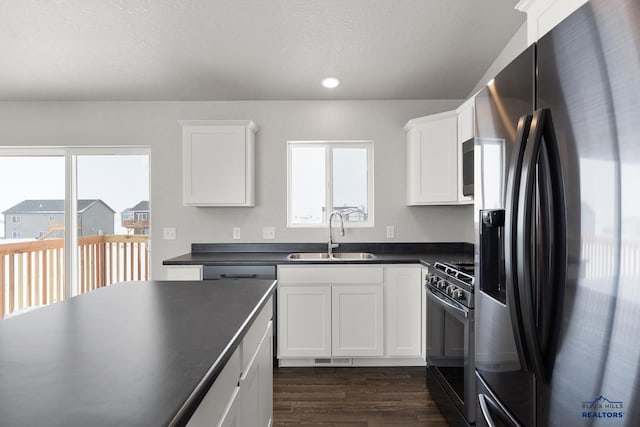 kitchen featuring a wealth of natural light, black fridge, a sink, dark countertops, and gas stove