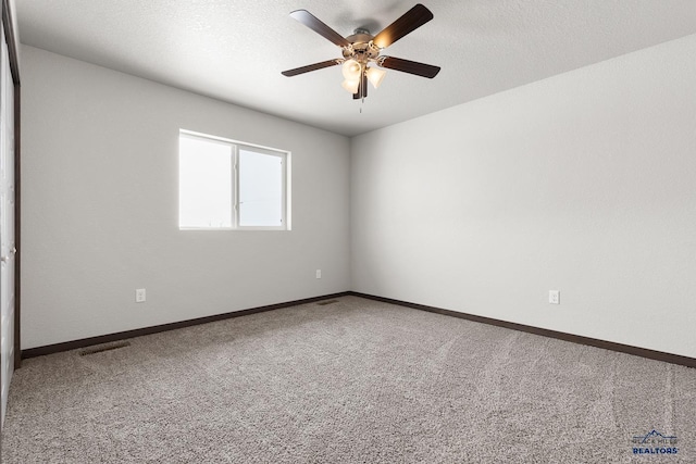 spare room featuring carpet flooring, baseboards, visible vents, and a textured ceiling