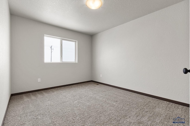 unfurnished room with carpet flooring, a textured ceiling, baseboards, and a textured wall