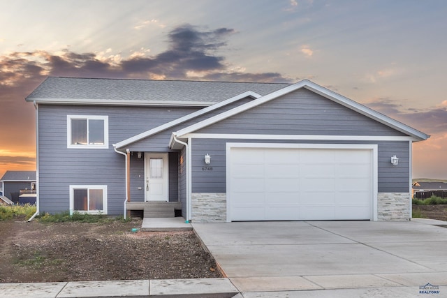 view of front facade featuring a garage, stone siding, and driveway