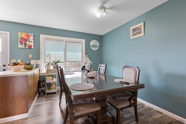 dining room featuring wood finished floors, baseboards, and a textured ceiling