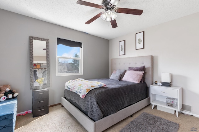 carpeted bedroom featuring visible vents, a textured ceiling, baseboards, and a ceiling fan