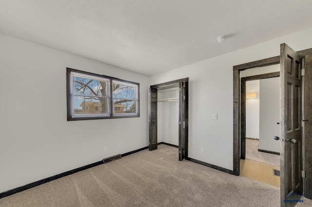 unfurnished bedroom with baseboards, visible vents, a closet, and light carpet