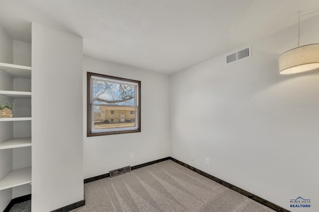 unfurnished room featuring visible vents, baseboards, and light colored carpet