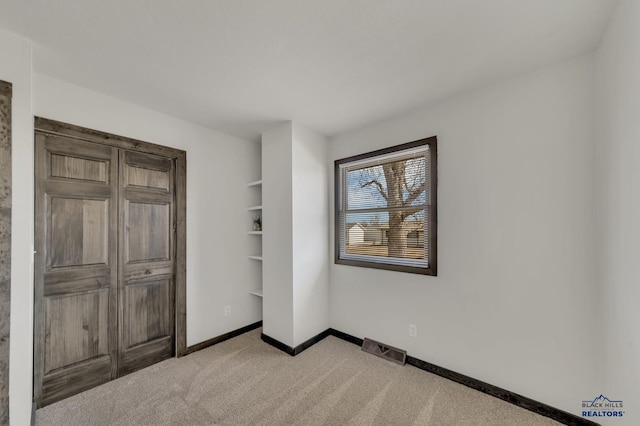 unfurnished bedroom featuring light carpet, visible vents, and baseboards