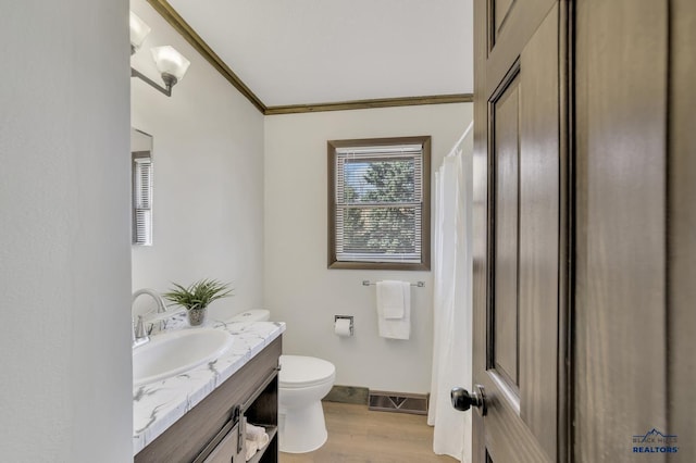 full bathroom featuring vanity, wood finished floors, baseboards, ornamental molding, and toilet