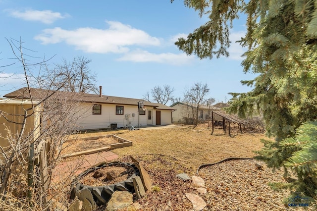 rear view of property featuring a patio and a vegetable garden