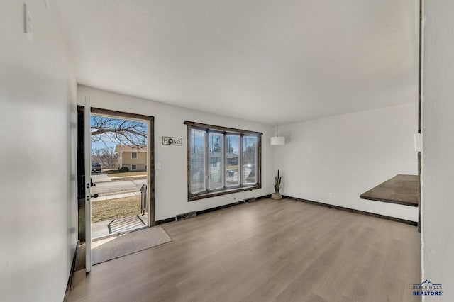 interior space with a wealth of natural light, visible vents, baseboards, and wood finished floors