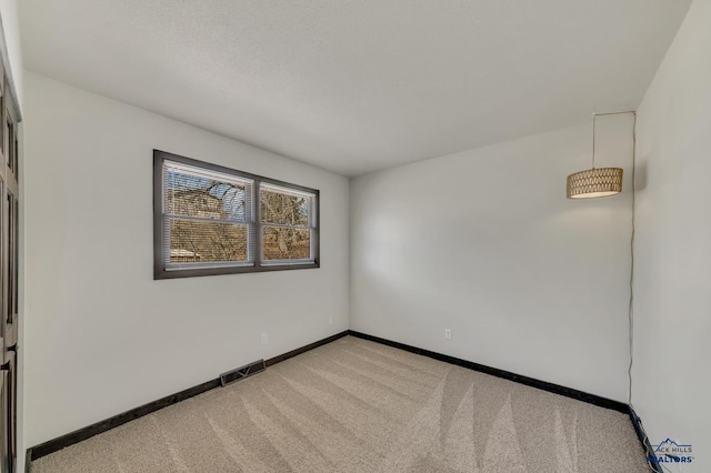 unfurnished room with visible vents, light colored carpet, and baseboards