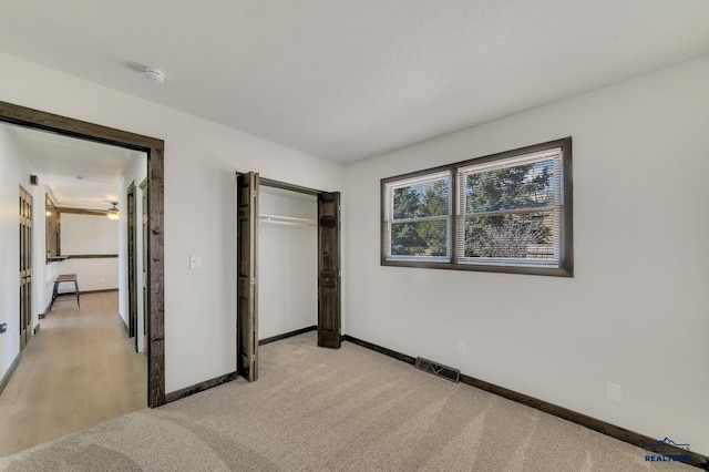 unfurnished bedroom featuring a closet, visible vents, light colored carpet, and baseboards