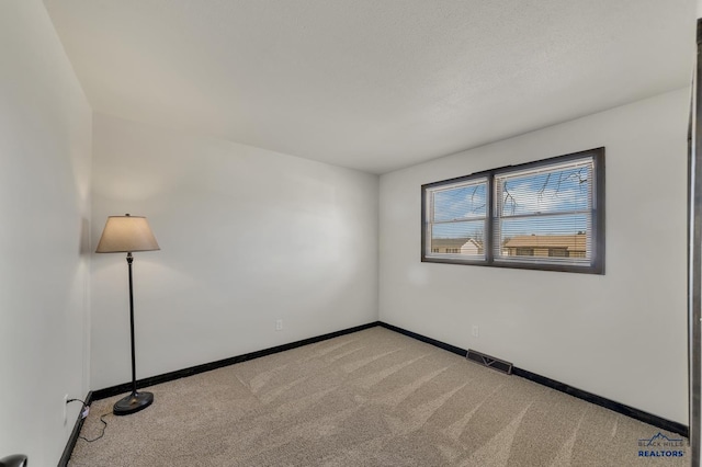 unfurnished room with baseboards, visible vents, and light carpet