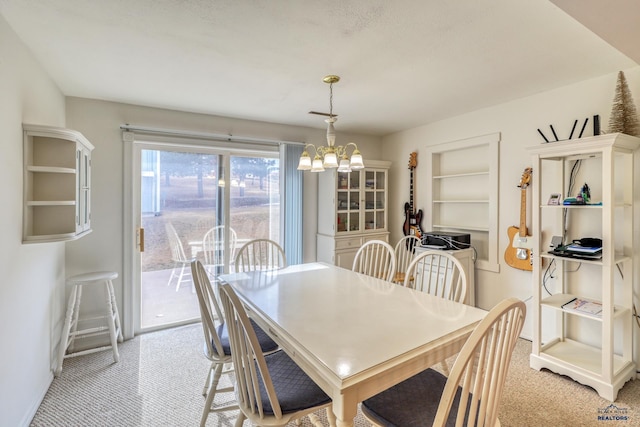 dining space featuring light carpet, a notable chandelier, and built in shelves