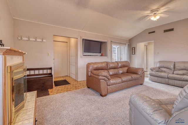 living room with visible vents, a textured ceiling, a glass covered fireplace, and vaulted ceiling