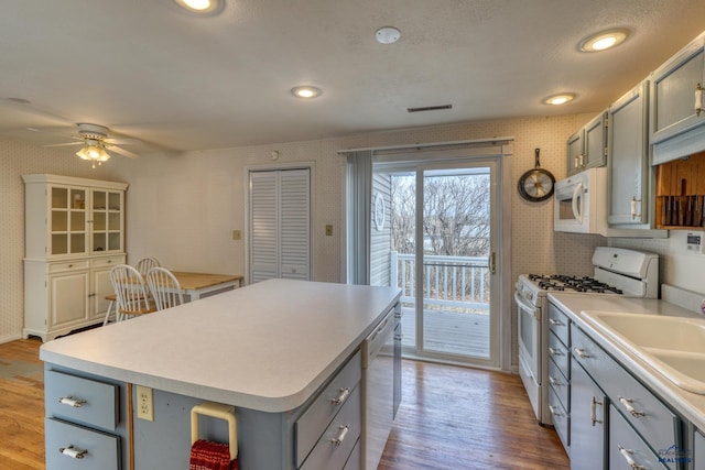 kitchen with light wood-type flooring, white appliances, gray cabinetry, and wallpapered walls