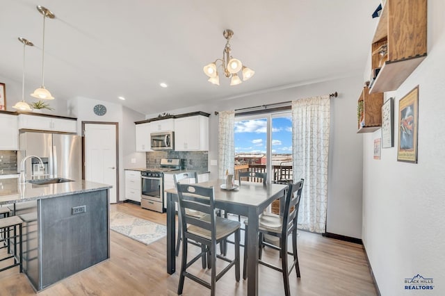 dining area featuring baseboards, lofted ceiling, recessed lighting, an inviting chandelier, and light wood-style floors