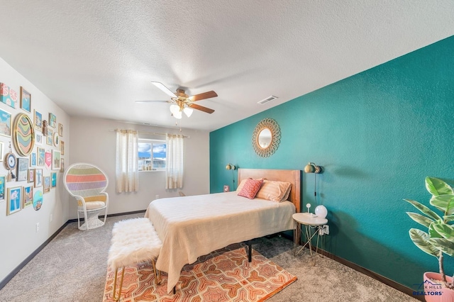 carpeted bedroom featuring a textured ceiling, baseboards, visible vents, and ceiling fan