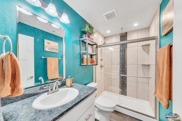 bathroom with visible vents, a stall shower, toilet, and vanity