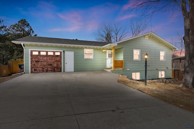 ranch-style home with concrete driveway, an attached garage, and fence