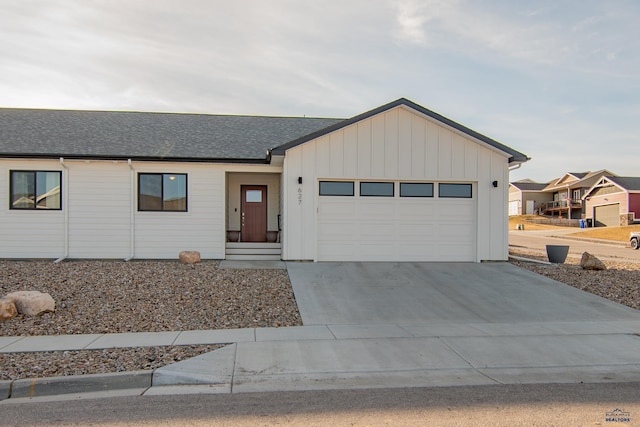 view of front of home with a shingled roof, board and batten siding, an attached garage, and concrete driveway