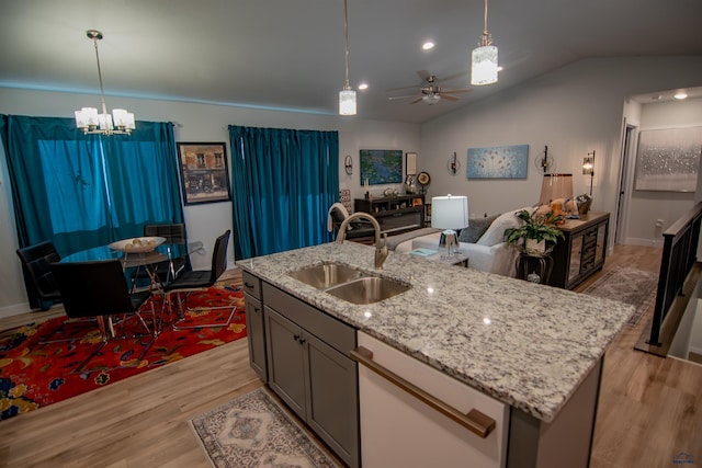 kitchen featuring light wood-style flooring, a sink, vaulted ceiling, pendant lighting, and open floor plan