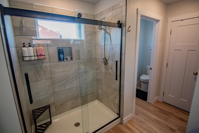 full bathroom featuring a shower stall, toilet, and wood finished floors