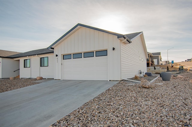 exterior space with board and batten siding, driveway, and a garage