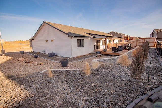 rear view of property featuring a deck and fence