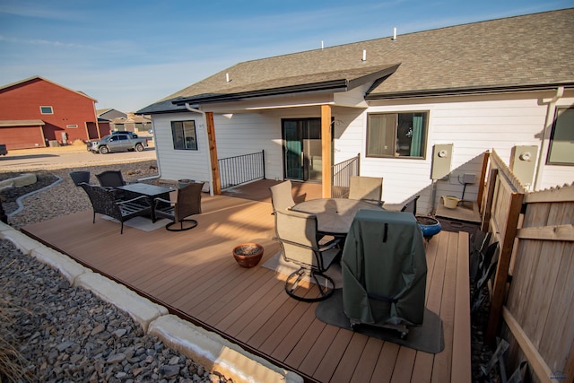 wooden terrace featuring outdoor dining area, area for grilling, and fence