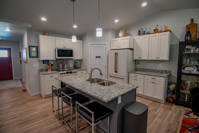 kitchen with built in microwave, white cabinets, freestanding refrigerator, and a sink