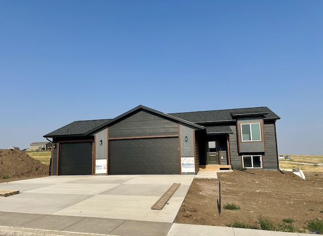 view of front of home featuring concrete driveway, a garage, and a shingled roof