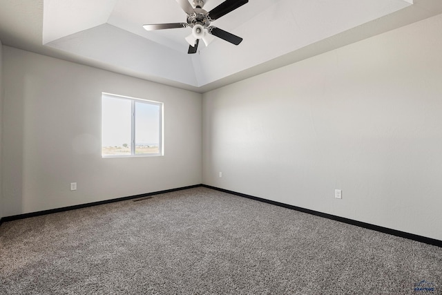 empty room with a ceiling fan, visible vents, baseboards, carpet floors, and a tray ceiling