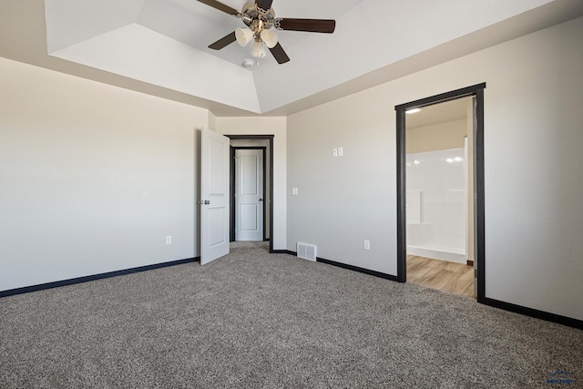 unfurnished bedroom with visible vents, baseboards, ensuite bathroom, light carpet, and a raised ceiling