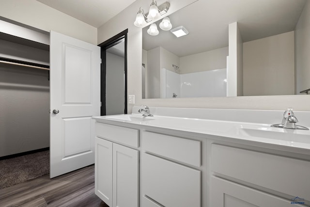 bathroom featuring a sink, a shower, wood finished floors, and double vanity