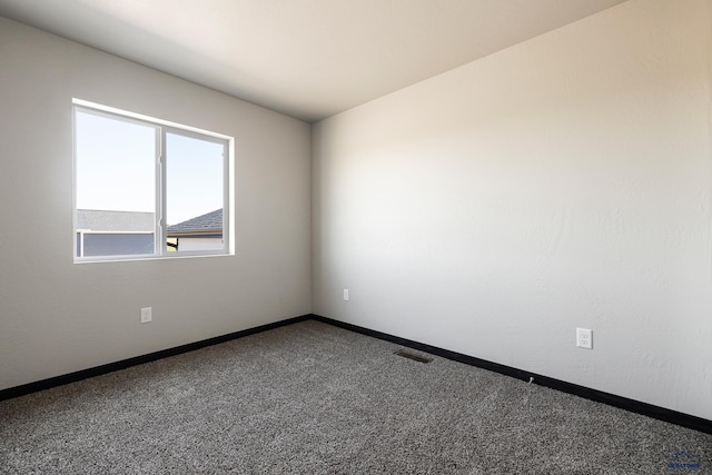 spare room with carpet flooring, visible vents, and baseboards