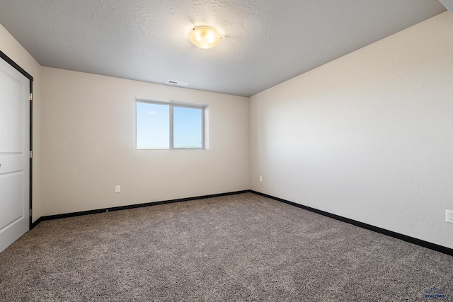 carpeted spare room featuring visible vents, baseboards, and a textured ceiling