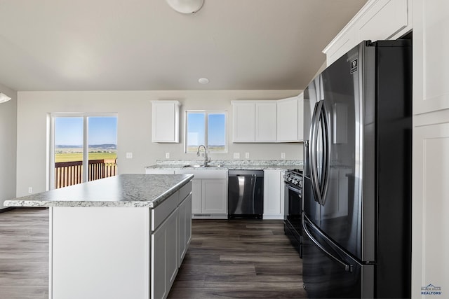 kitchen with a kitchen island, dark wood-type flooring, appliances with stainless steel finishes, white cabinets, and a sink