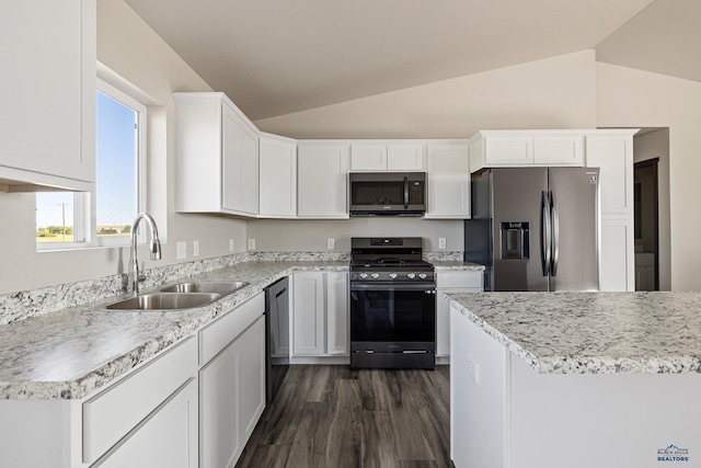 kitchen with a sink, stainless steel appliances, vaulted ceiling, and white cabinetry