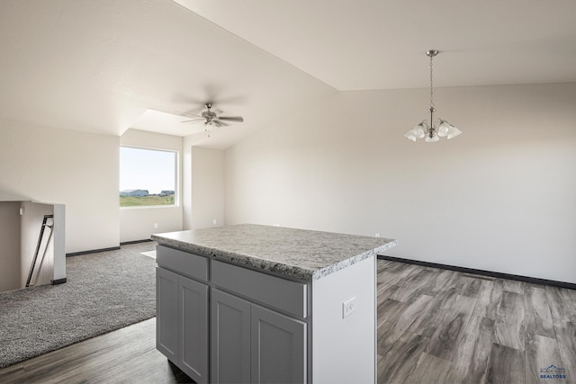 kitchen featuring baseboards, a kitchen island, gray cabinets, ceiling fan with notable chandelier, and open floor plan