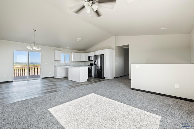 unfurnished living room featuring dark colored carpet, baseboards, ceiling fan, and vaulted ceiling