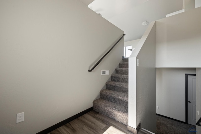 staircase with visible vents, baseboards, and wood finished floors