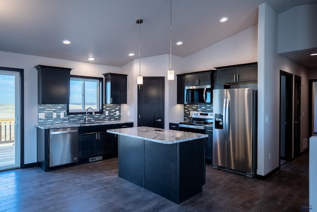 kitchen featuring light stone counters, lofted ceiling, a sink, appliances with stainless steel finishes, and a center island