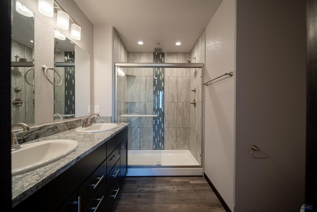 full bath with a sink, wood finished floors, and a stall shower